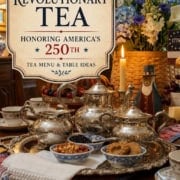 A silver tea set with cups, cookies, and nuts on a decorated table, featuring a sign that reads “A Revolutionary Tea Honoring America’s 250th; Tea Menu & Table Ideas; 31Daily.”.