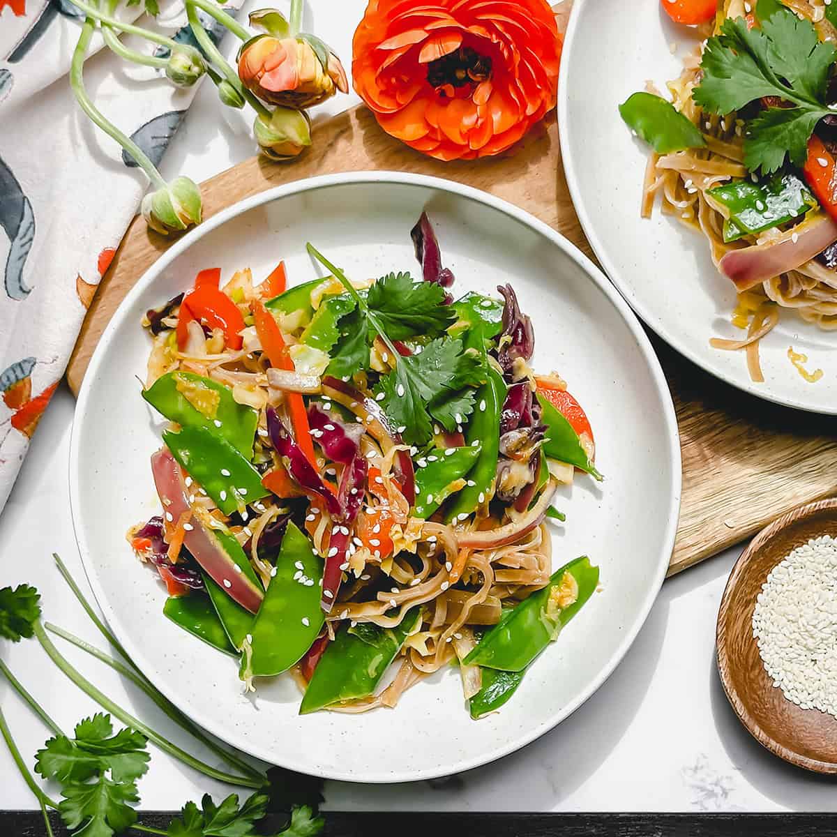 A plate of vegetable stir-fry with snow peas, carrots, red cabbage, and sesame seeds, garnished with fresh cilantro-a perfect choice for easy June 30 minute dinners.