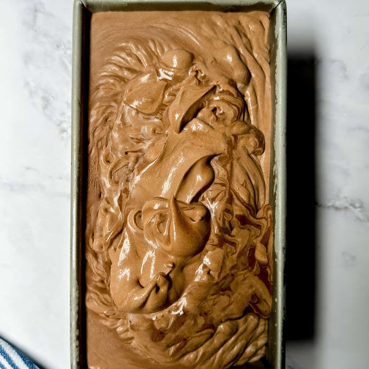 No-churn chocolate ice cream mixture swirled in a metal loaf pan before freezing.