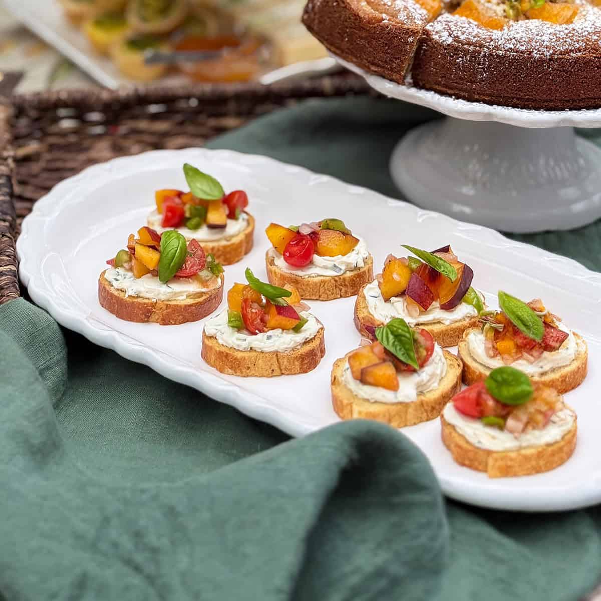 Sliced baguette rounds topped with creamy goat cheese, spiced peach salsa, spread, and basil leaves served for an August afternoon tea.