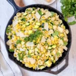 Corn and Zucchini Pasta in a cast iron skillet and topped with fresh herbs and Parmesan Cheese.