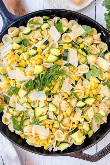 Corn and Zucchini Pasta in a cast iron skillet and topped with fresh herbs and Parmesan Cheese.