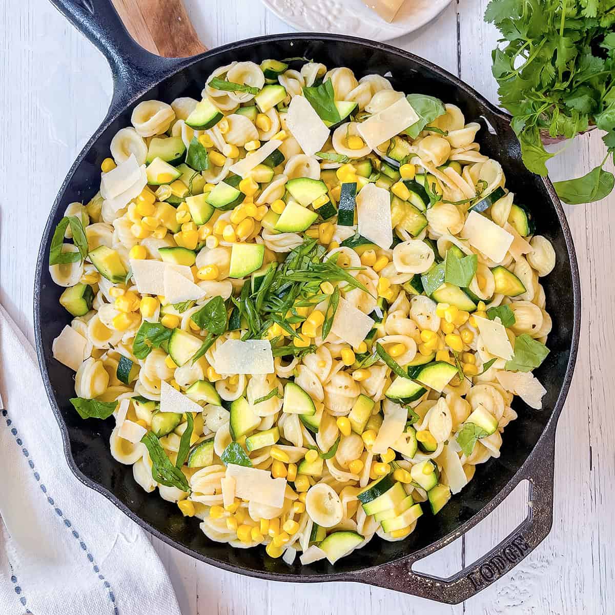 Corn and Zucchini Pasta in a cast iron skillet and topped with fresh herbs and Parmesan Cheese.