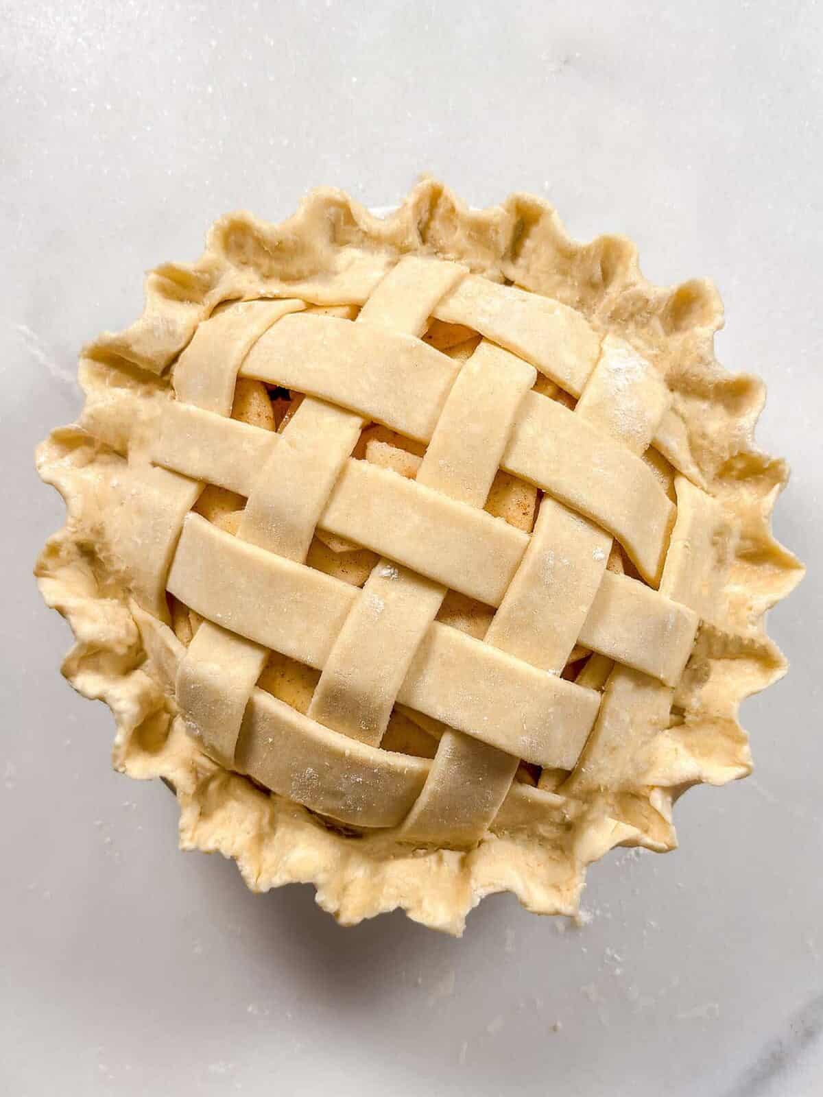 Unbaked apple pie with crimped all butter pie crust edges.