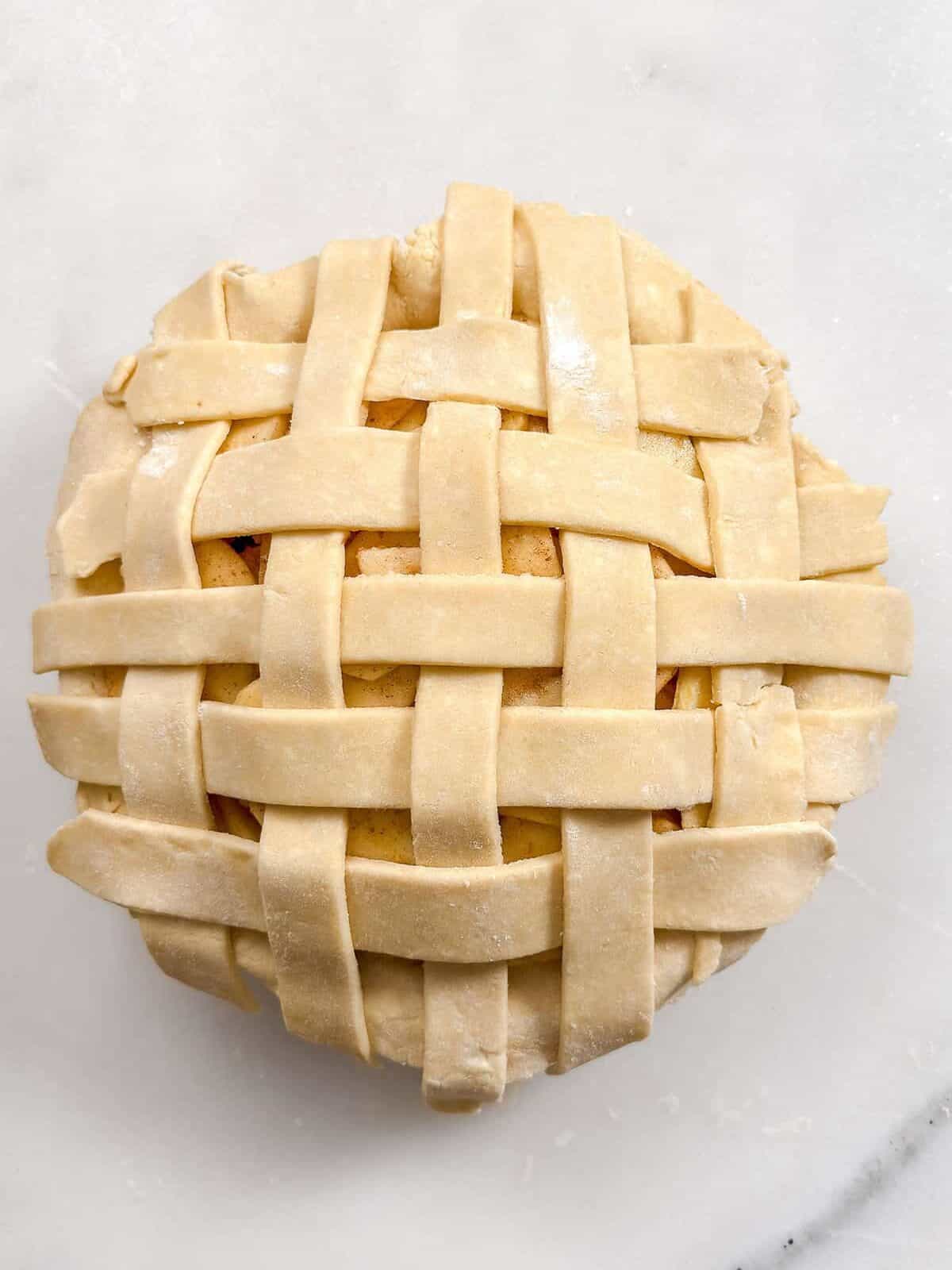 Unbaked lattice all butter pie crust topping sliced apples and ready for baking.