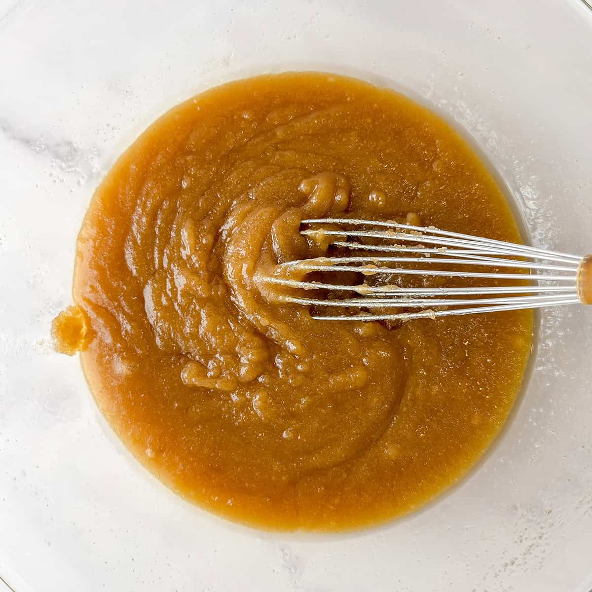 Melted butter, brown sugar, granulated sugar, eggs and vanilla whisked together in a glass bowl.