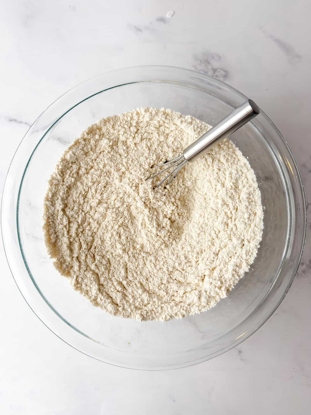 Flour, baking powder, cinnamon, nutmeg, cardamom, and salt in a glass bowl.