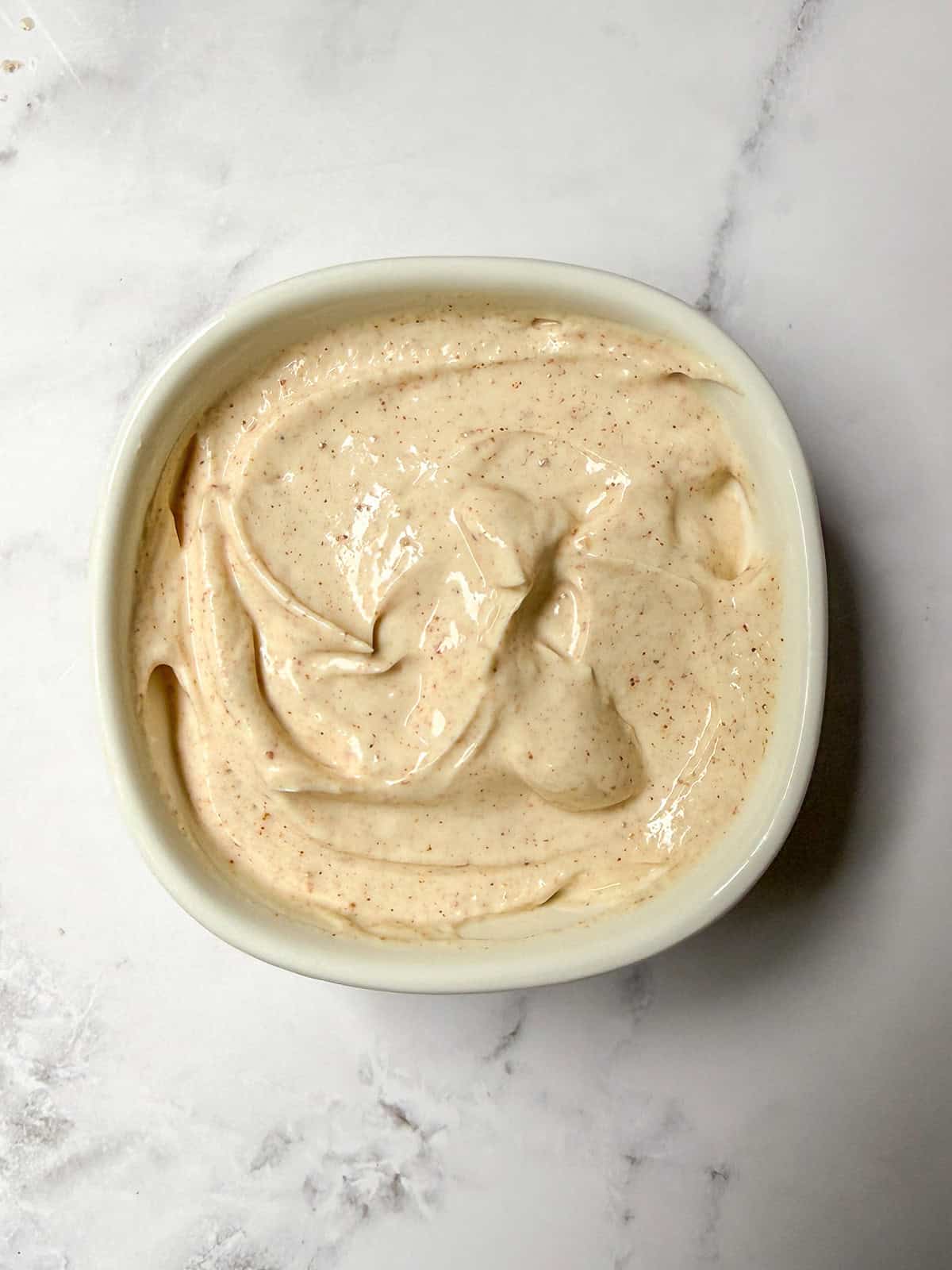 A white bowl filled with creamy and seasoned, chicken fajita sauce for serving with the meal.