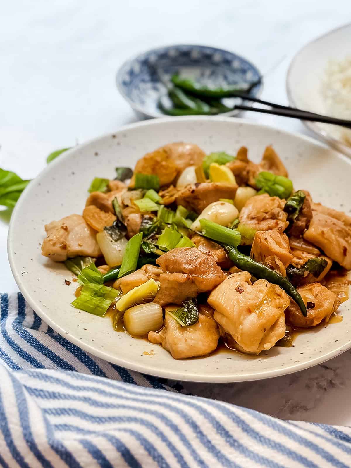 Close-up of Three Cup Chicken with tender chicken thighs, ginger, garlic, scallions, basil, and red chile.