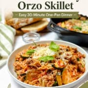 Ground Turkey and Orzo Skillet with Zucchini in a bowl topped with grated mozzarella and fresh herbs and text "Cheesy Ground Turkey Orzo Skillet."