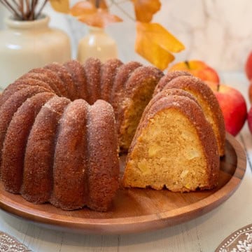Sliced apple cider donut Bundt cake with a cinnamon sugar coating and pieces of fresh apple in the moist crumb.