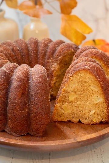 Sliced apple cider donut Bundt cake with a cinnamon sugar coating and pieces of fresh apple in the moist crumb.