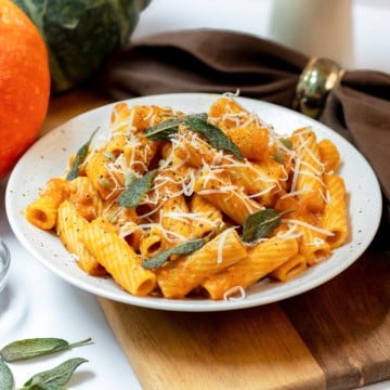 Close view of creamy pumpkin sage pasta with rigatoni, crisp sage leaves, Parmesan, black pepper, and pepitas.