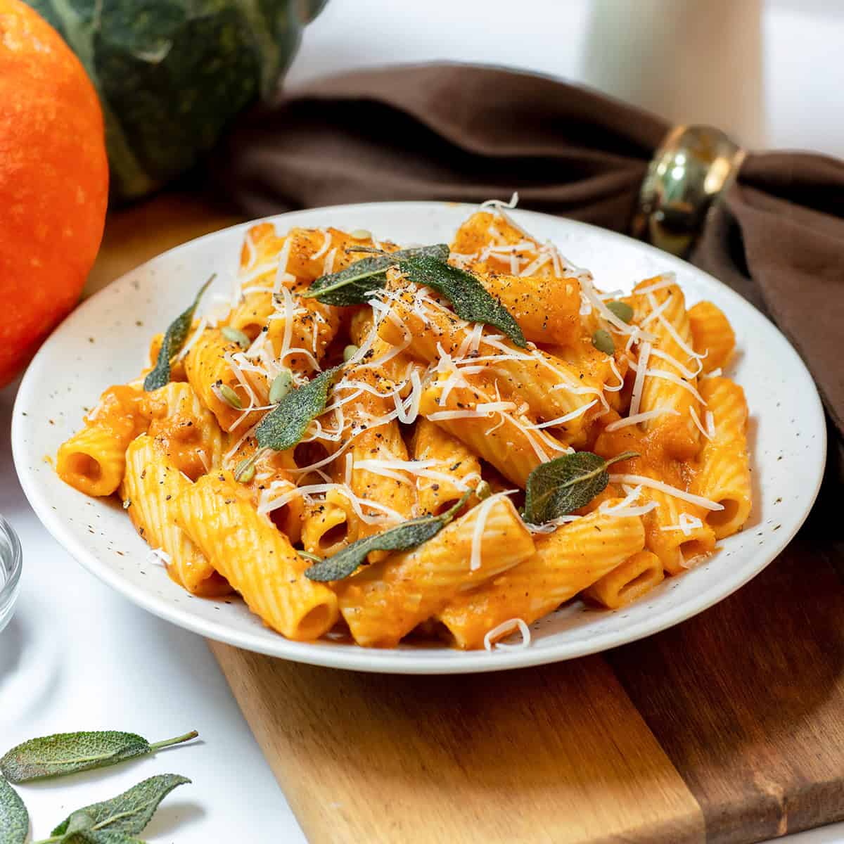 Close view of creamy pumpkin sage pasta with rigatoni, crisp sage leaves, Parmesan, black pepper, and pepitas.