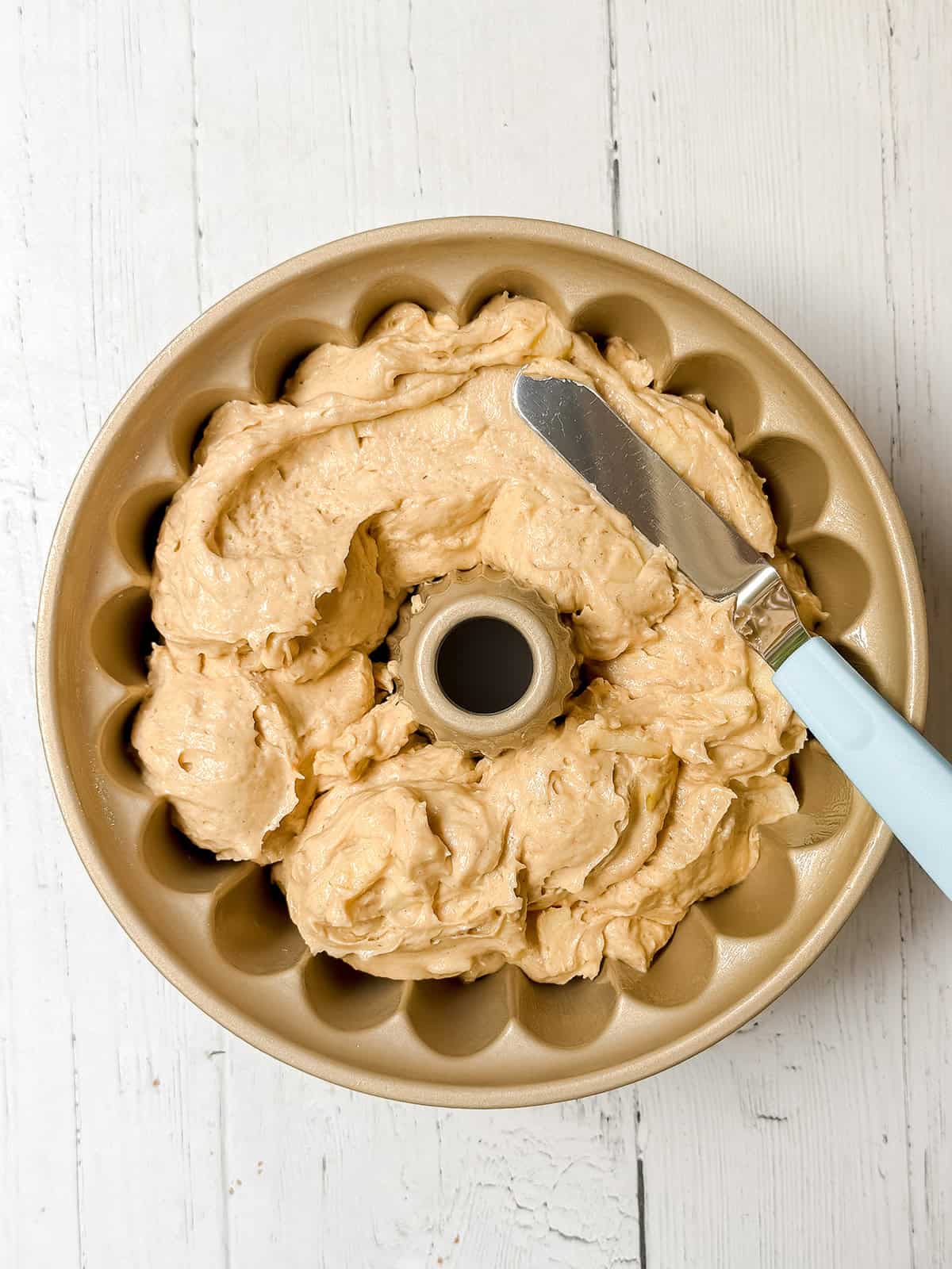 Spreading cider cake batter with an offset spatula in a Bundt pan.