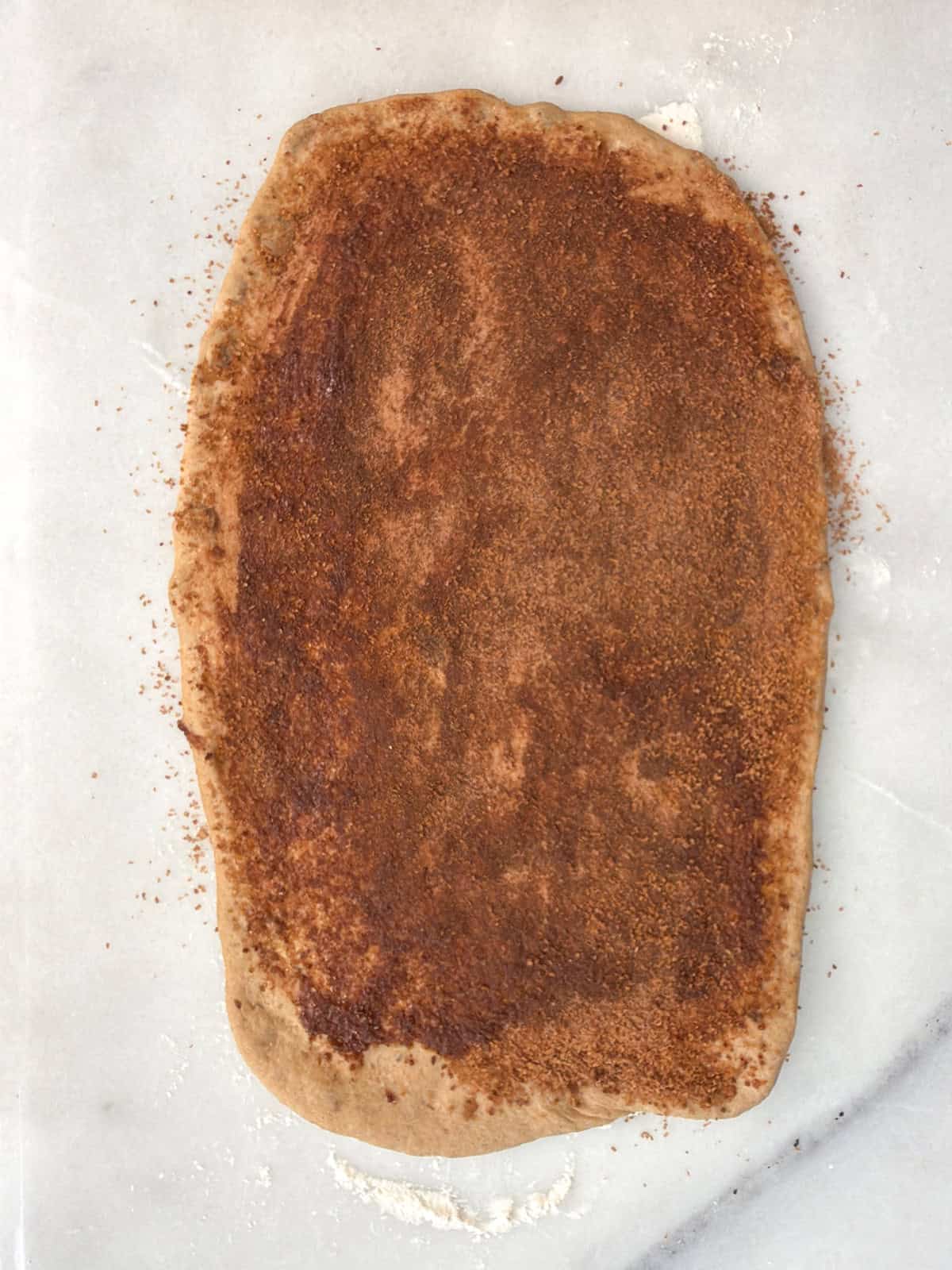 Cinnamon sugar filling spread evenly over rolled whole wheat raisin bread dough.