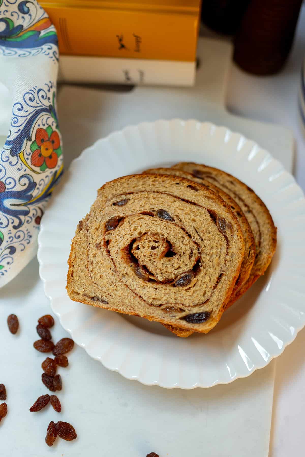 Slices of whole wheat cinnamon raisin swirl bread arranged on a white plate.