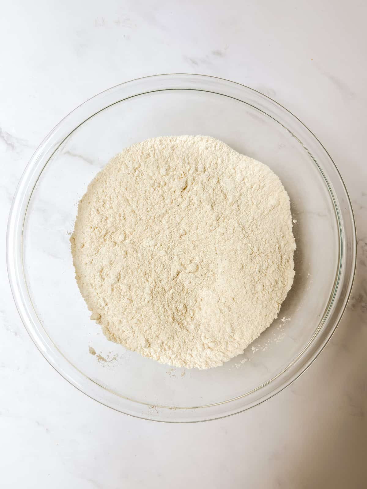 Flour, sugar, baking powder, salt, and cinnamon whisk together in a glass bowl.