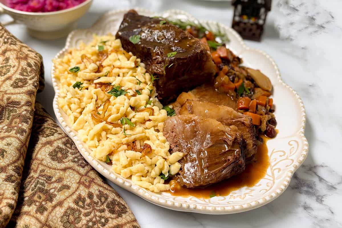 Sliced apple cider sauerbraten with rich gravy, Sp&auml;tzle, carrots, raisins, and red cabbage.