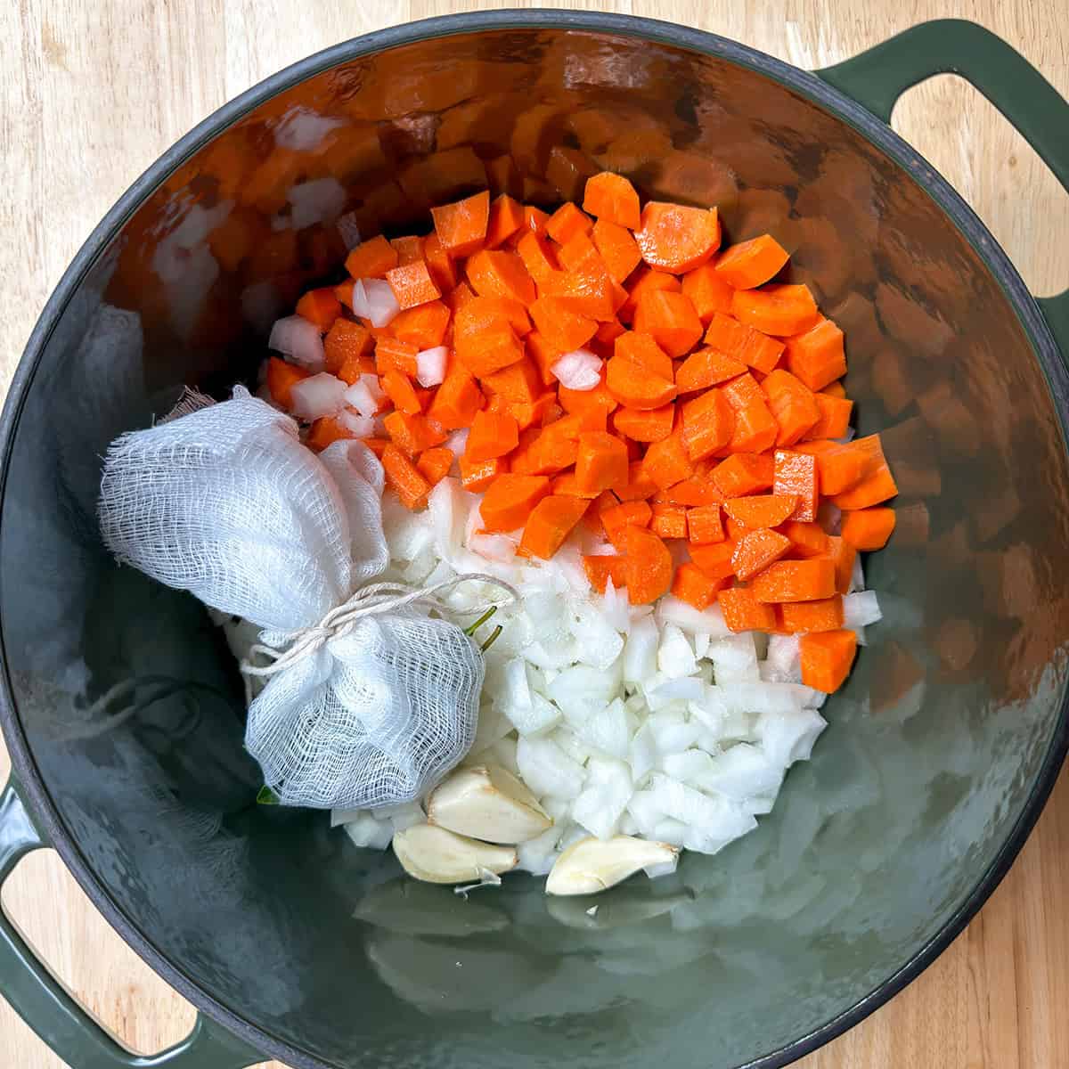 Chopped carrots, onion, garlic, and a cheesecloth bouquet garni in a Dutch oven for sauerbraten marinade.