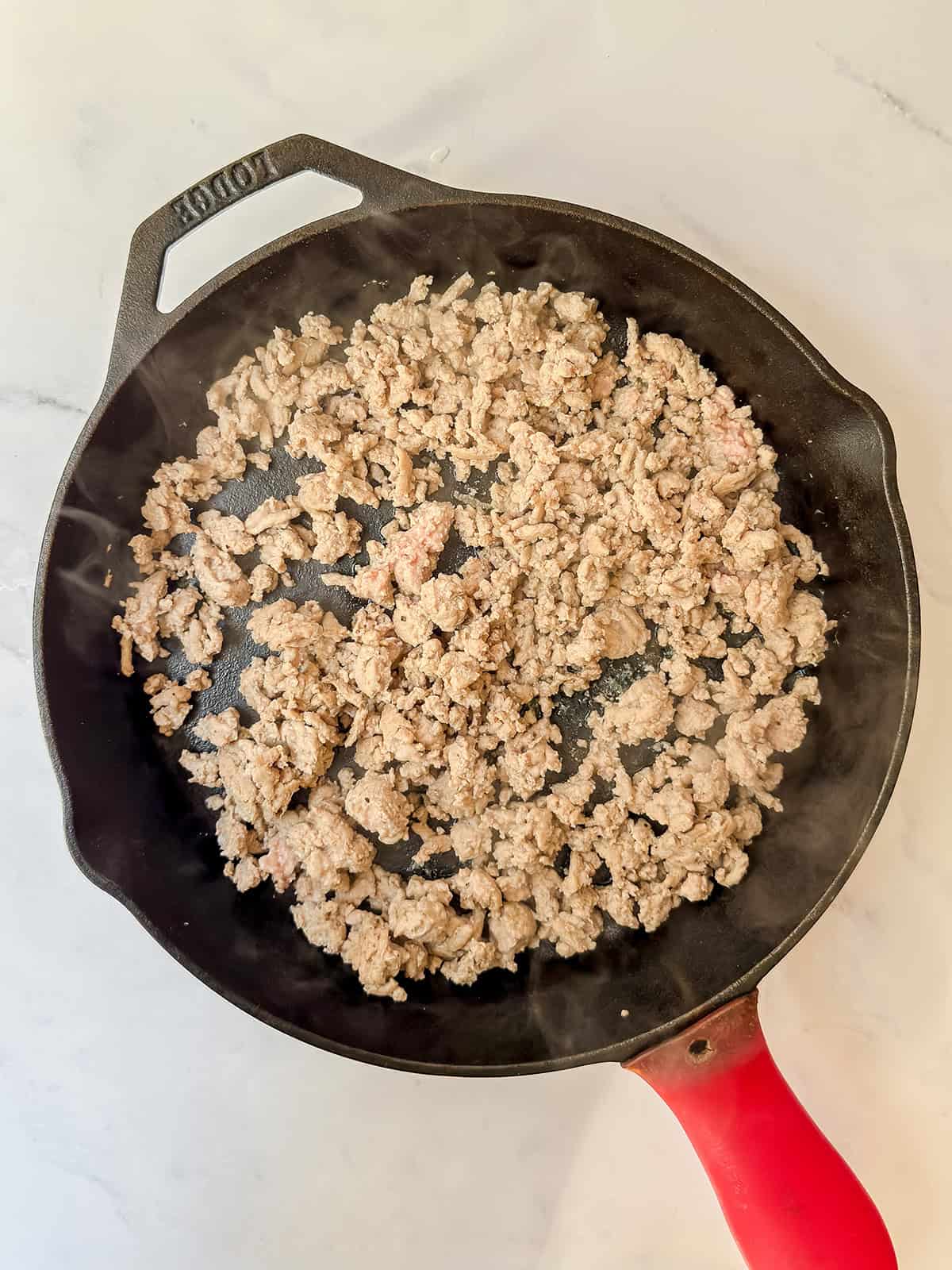 Ground turkey browning in a cast iron skillet.